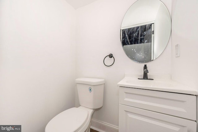 bathroom with toilet, vanity, and baseboards