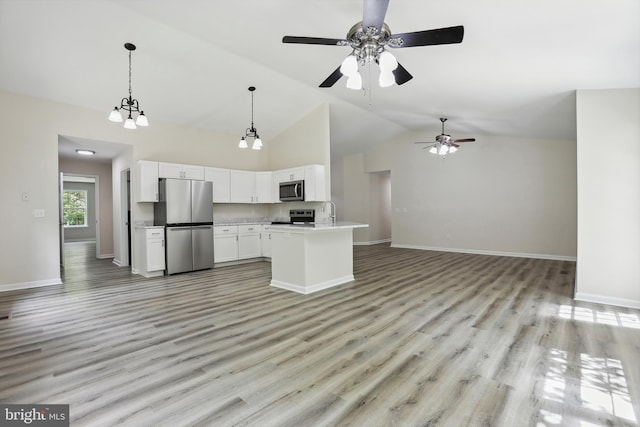 kitchen with stainless steel appliances, open floor plan, white cabinetry, light countertops, and baseboards