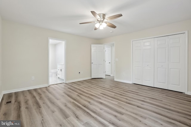 unfurnished bedroom with light wood-style floors, a closet, baseboards, and connected bathroom