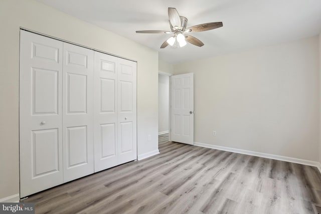unfurnished bedroom with wood finished floors, a closet, baseboards, and a ceiling fan