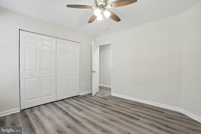 unfurnished bedroom featuring wood finished floors, baseboards, and a closet