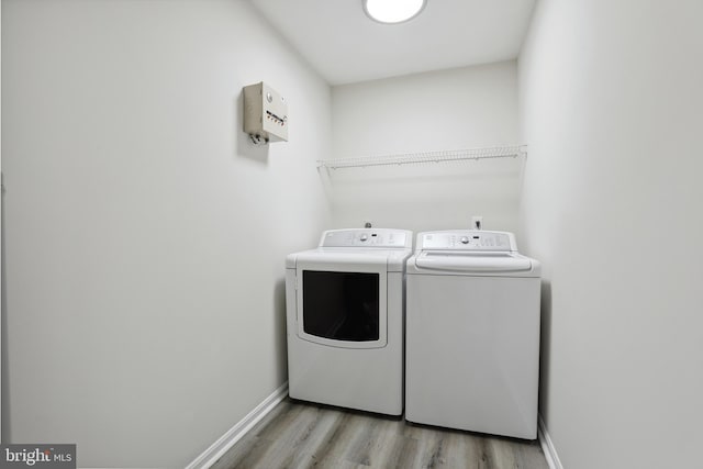 laundry area with washer and dryer, light wood-style flooring, and baseboards