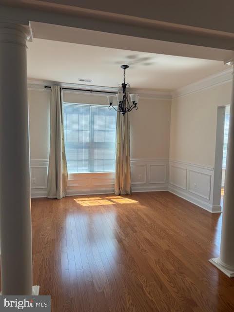 9200 Charleston Dr Unit 207, Manassas, VA 20110 - unfurnished room featuring decorative columns, ornamental molding, a chandelier, wood finished floors, and a decorative wall