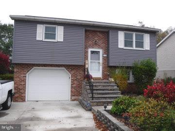 raised ranch with a garage, brick siding, and driveway