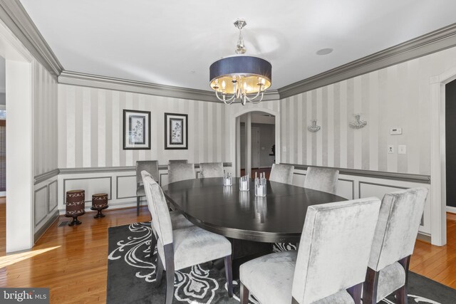 17621 Auburn Village Dr, Sandy Spring, MD 20860 - dining space featuring arched walkways, a chandelier, wallpapered walls, wood finished floors, and crown molding