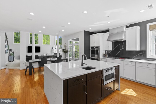 17621 Auburn Village Dr, Sandy Spring, MD 20860 - kitchen featuring a sink, wall chimney range hood, appliances with stainless steel finishes, backsplash, and white cabinetry