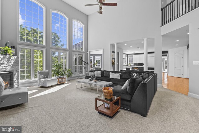 17621 Auburn Village Dr, Sandy Spring, MD 20860 - carpeted living area with a high ceiling, a ceiling fan, ornate columns, a stone fireplace, and baseboards