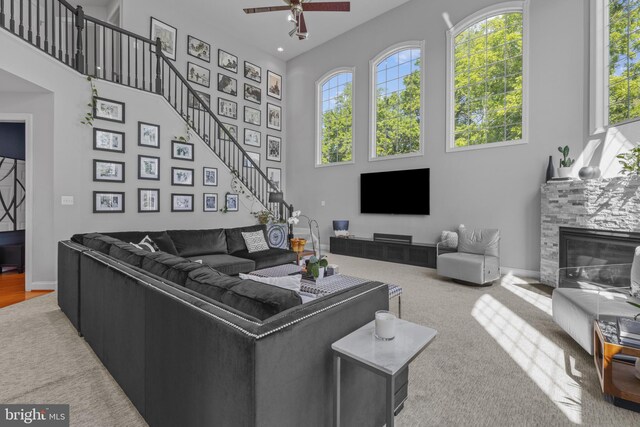 17621 Auburn Village Dr, Sandy Spring, MD 20860 - living area with a towering ceiling, a glass covered fireplace, healthy amount of natural light, a ceiling fan, and stairway