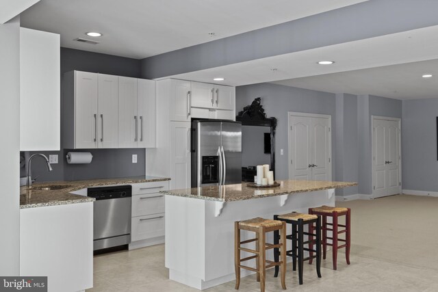 17621 Auburn Village Dr, Sandy Spring, MD 20860 - kitchen featuring stainless steel appliances, a sink, a kitchen island, light stone counters, and white cabinets