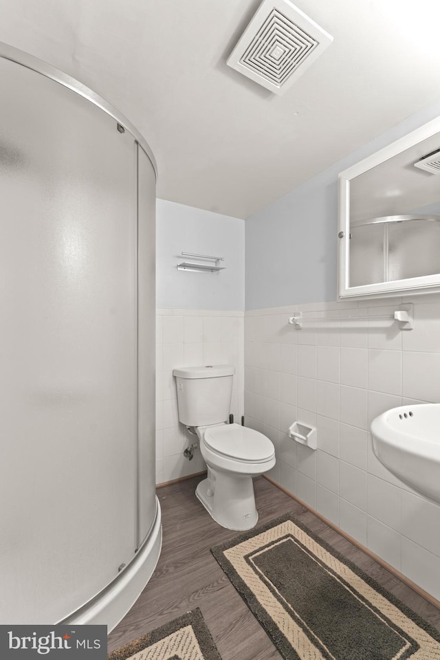 5911 Cecil Ave, Baltimore, MD 21207 - full bath with a shower stall, tile walls, wood finished floors, toilet, and wainscoting