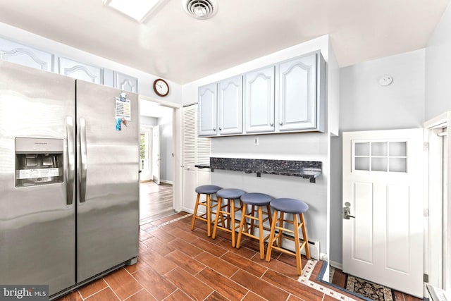 5911 Cecil Ave, Baltimore, MD 21207 - kitchen with stainless steel fridge with ice dispenser, a breakfast bar area, baseboard heating, dark wood-style flooring, and baseboards