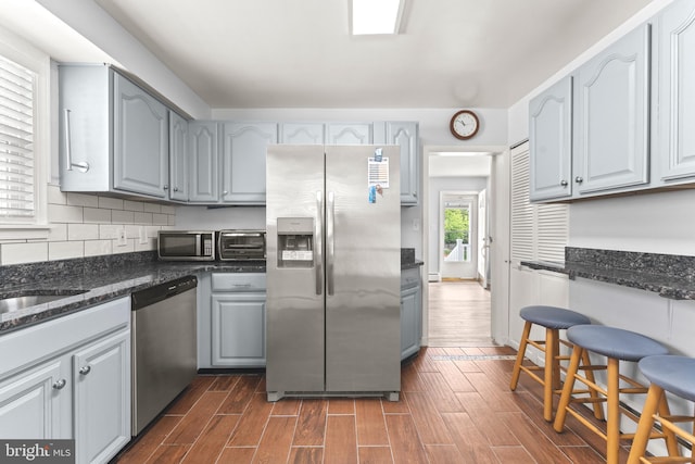 5911 Cecil Ave, Baltimore, MD 21207 - kitchen featuring stainless steel appliances, dark wood-style flooring, dark stone countertops, and gray cabinetry