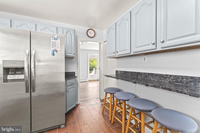 5911 Cecil Ave, Baltimore, MD 21207 - kitchen featuring stainless steel fridge with ice dispenser, wood tiled floors, dark stone countertops, gray cabinets, and a kitchen bar