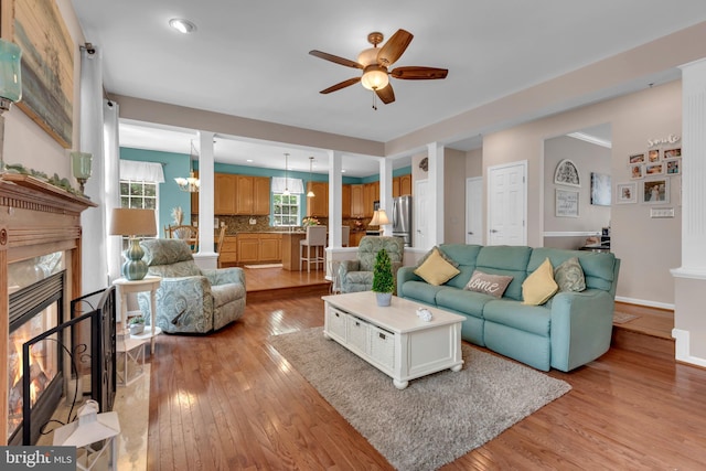 8139 Showcase Ct, Pasadena, MD 21122 - living area featuring a ceiling fan, a fireplace, light wood-style flooring, baseboards, and a chandelier