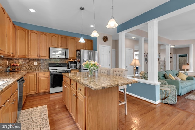 8139 Showcase Ct, Pasadena, MD 21122 - kitchen featuring appliances with stainless steel finishes, decorative columns, a breakfast bar, light stone countertops, and tasteful backsplash