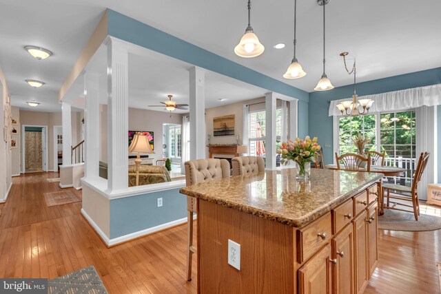 8139 Showcase Ct, Pasadena, MD 21122 - kitchen featuring a kitchen bar, light wood-type flooring, baseboards, a kitchen island, and light stone counters