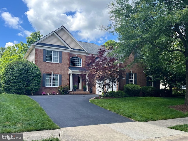 view of front of property with brick siding, asphalt driveway, and a front yard