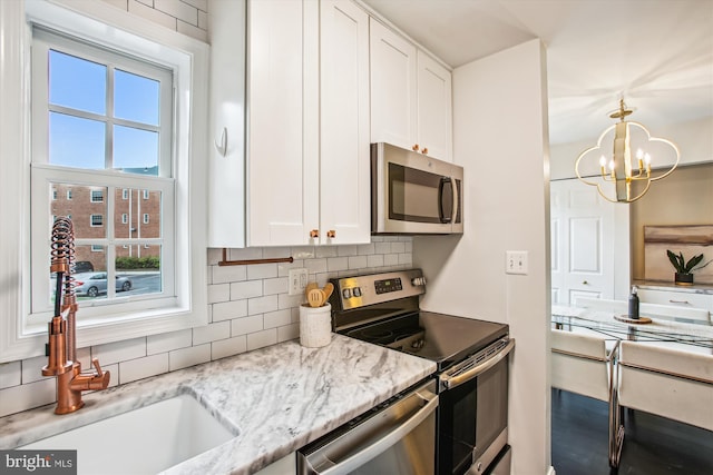 1712 W Abingdon Dr Unit 102, Alexandria, VA 22314 - kitchen with appliances with stainless steel finishes, white cabinets, decorative backsplash, a chandelier, and light stone counters