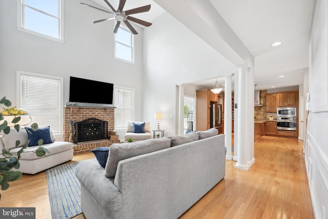 301 Nottingham Ln, Queenstown, MD 21658 - living area featuring ornate columns, a ceiling fan, light wood-style flooring, a towering ceiling, and a fireplace