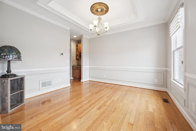 301 Nottingham Ln, Queenstown, MD 21658 - spare room featuring a chandelier, a tray ceiling, crown molding, and light wood-type flooring