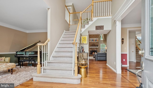 56 Saxon Way, Skillman, NJ 08558 - stairway featuring wood finished floors, baseboards, crown molding, a large fireplace, and a towering ceiling