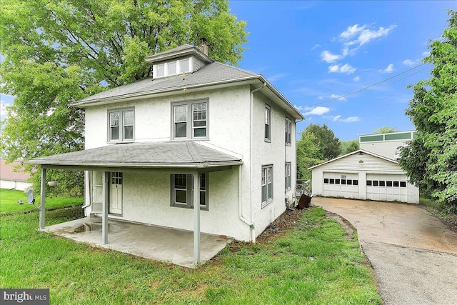 view of front of house with stucco siding, a chimney, an outbuilding, and a front lawn