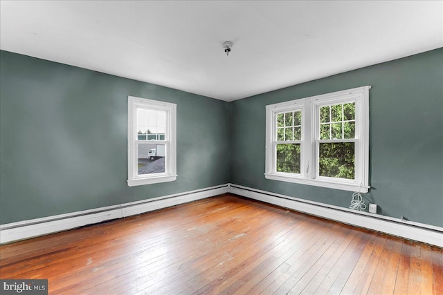 empty room with a baseboard radiator, wood-type flooring, and baseboards