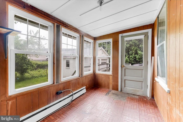 unfurnished sunroom with a baseboard radiator, wood walls, brick patterned flooring, and lofted ceiling