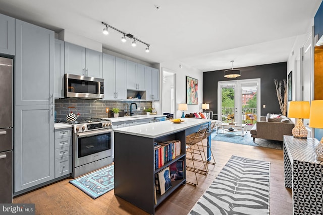6803 Cameron Dr NW Unit 105, Washington, DC 20012 - kitchen featuring appliances with stainless steel finishes, light countertops, a center island, light wood finished floors, and open shelves
