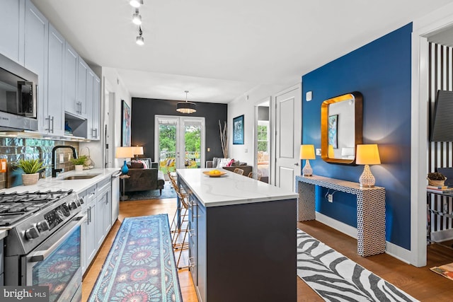 6803 Cameron Dr NW Unit 105, Washington, DC 20012 - kitchen with appliances with stainless steel finishes, a sink, french doors, a kitchen island, and light wood finished floors