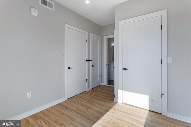 hallway featuring light wood finished floors and baseboards