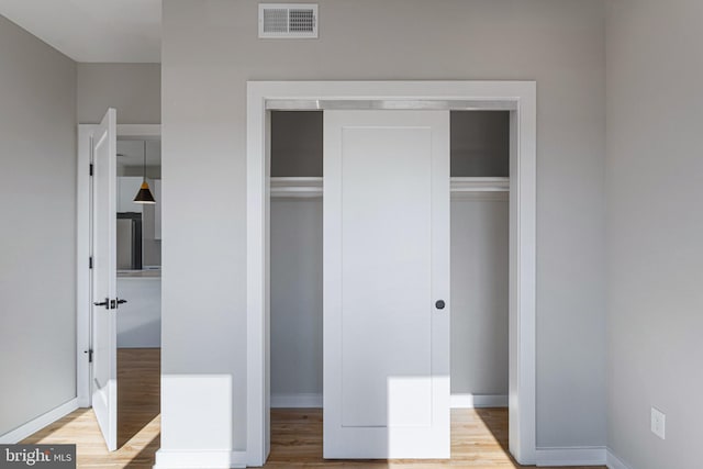 unfurnished bedroom featuring light wood finished floors, a closet, and baseboards