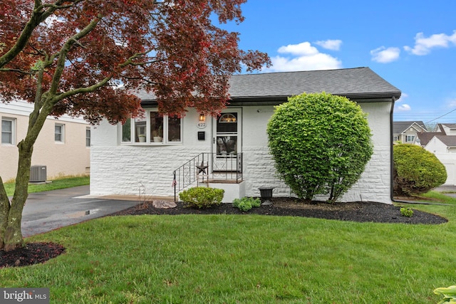 422 Jefferson Ave, Langhorne, PA 19047 - obstructed view of property with central AC unit, a front yard, stone siding, and a shingled roof