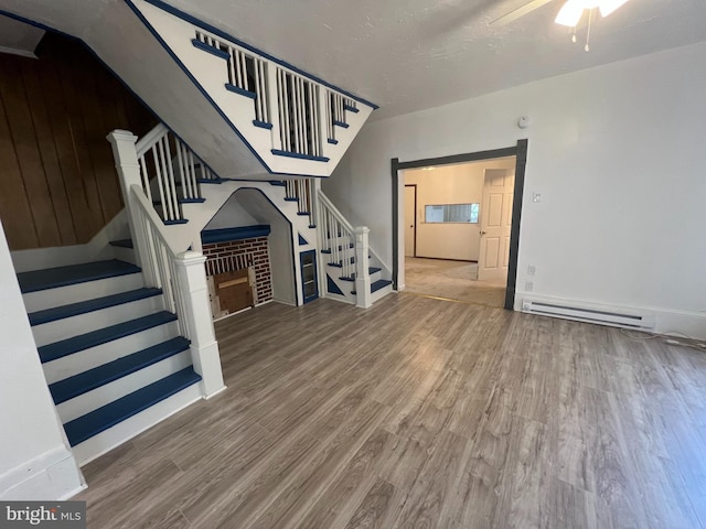 19 S Gold St, Shamokin, PA 17872 - unfurnished living room featuring baseboard heating, stairs, wood finished floors, ceiling fan, and baseboards
