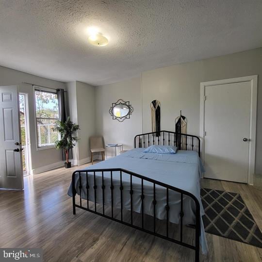 bedroom featuring wood finished floors, a textured ceiling, and baseboards