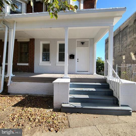 entrance to property with covered porch and brick siding