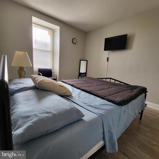 bedroom with dark wood-style flooring and baseboards