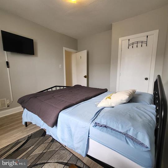 bedroom featuring wood finished floors, baseboards, and a closet