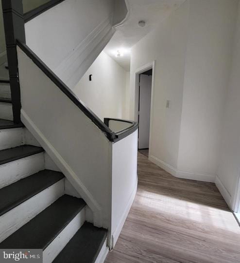 stairway with wood finished floors and baseboards