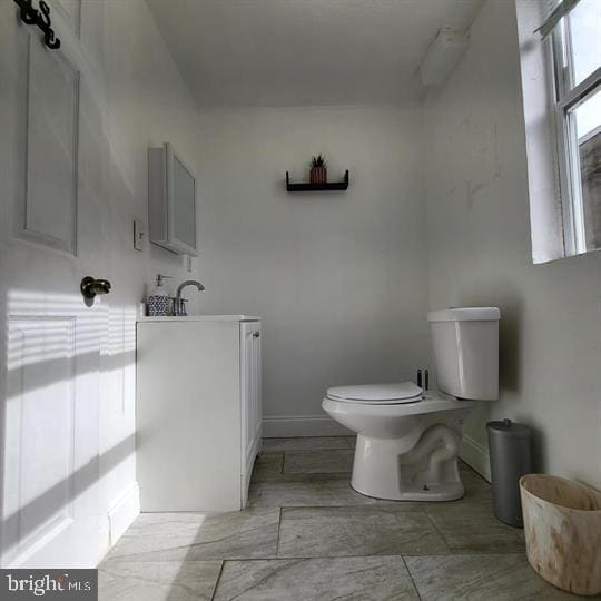 bathroom with toilet, baseboards, and vanity