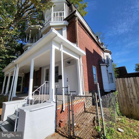 view of front of home featuring brick siding, a porch, and a gate