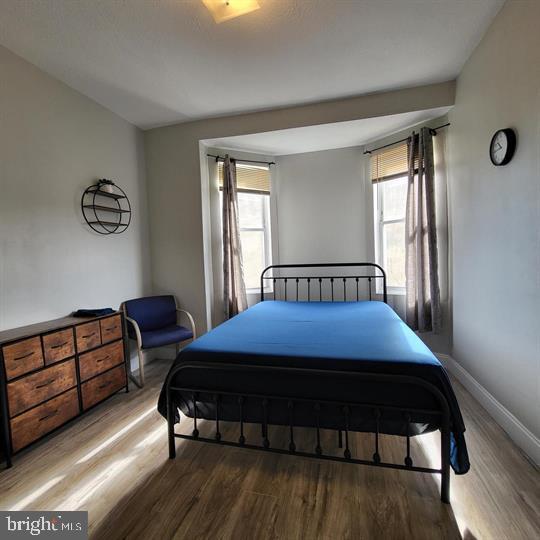 bedroom with wood finished floors, multiple windows, and baseboards