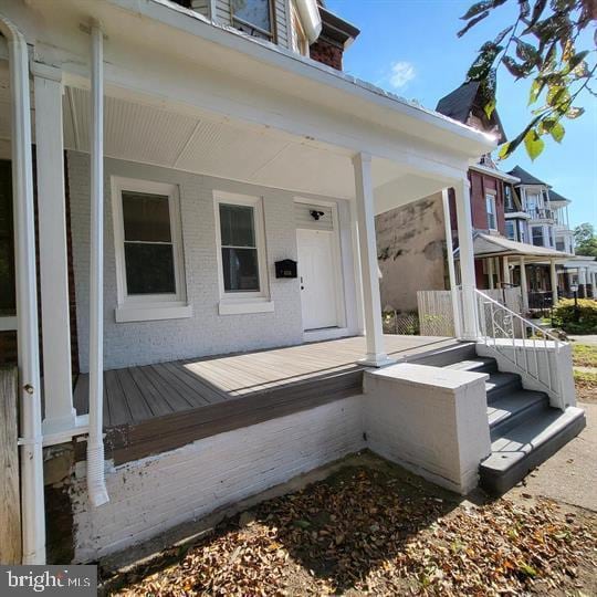 view of exterior entry with covered porch and brick siding