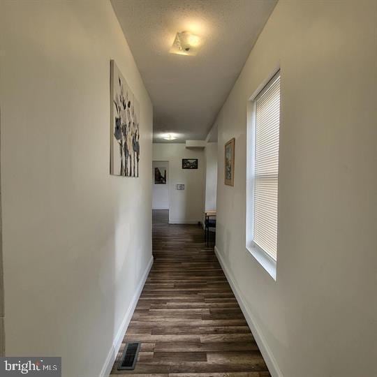 corridor with dark wood finished floors and baseboards