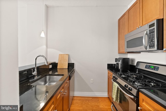 2120 Vermont Ave NW Unit 411, Washington, DC 20001 - kitchen featuring appliances with stainless steel finishes, a sink, dark stone countertops, baseboards, and brown cabinetry