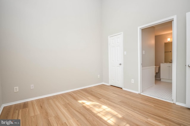 3313 Wyndham Cir Unit 4209, Alexandria, VA 22302 - unfurnished bedroom with light wood-style flooring, baseboards, and connected bathroom