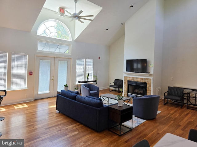 3313 Wyndham Cir Unit 4209, Alexandria, VA 22302 - living area with high vaulted ceiling, a tiled fireplace, ceiling fan, wood finished floors, and plenty of natural light