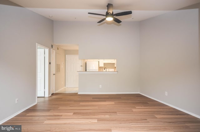 3313 Wyndham Cir Unit 4209, Alexandria, VA 22302 - unfurnished room featuring ceiling fan, baseboards, light wood-type flooring, and a towering ceiling