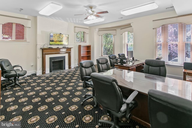 carpeted office with a fireplace, baseboards, and a ceiling fan