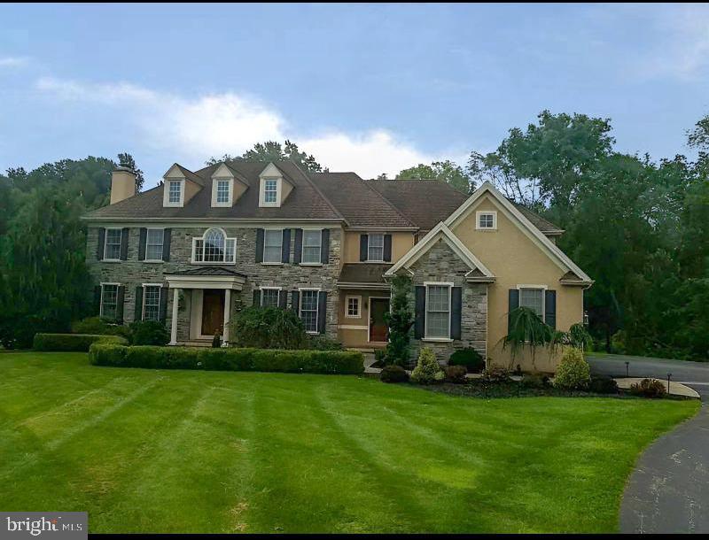 colonial home with stone siding, a front lawn, a chimney, and stucco siding